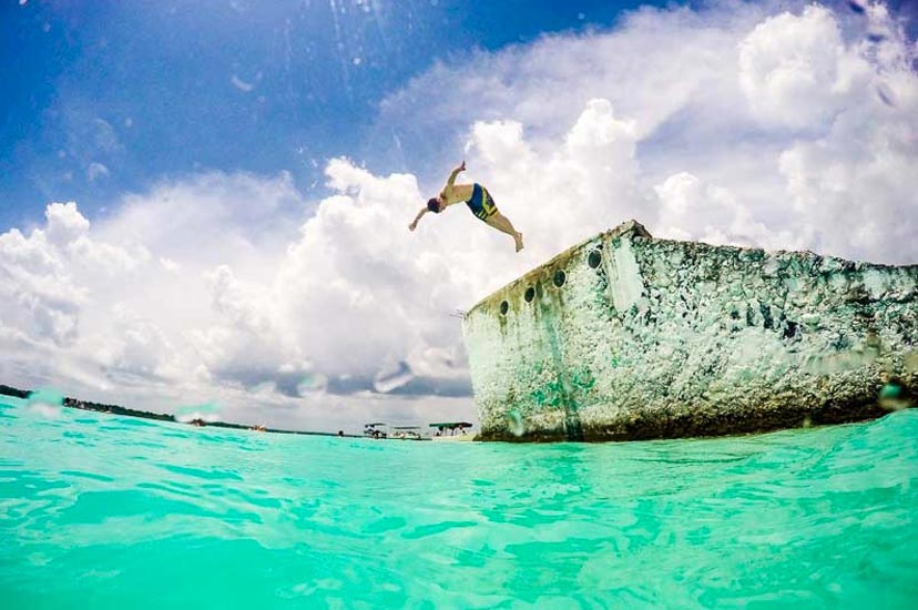 hombre joven saltando al agua en laguna de bacalar